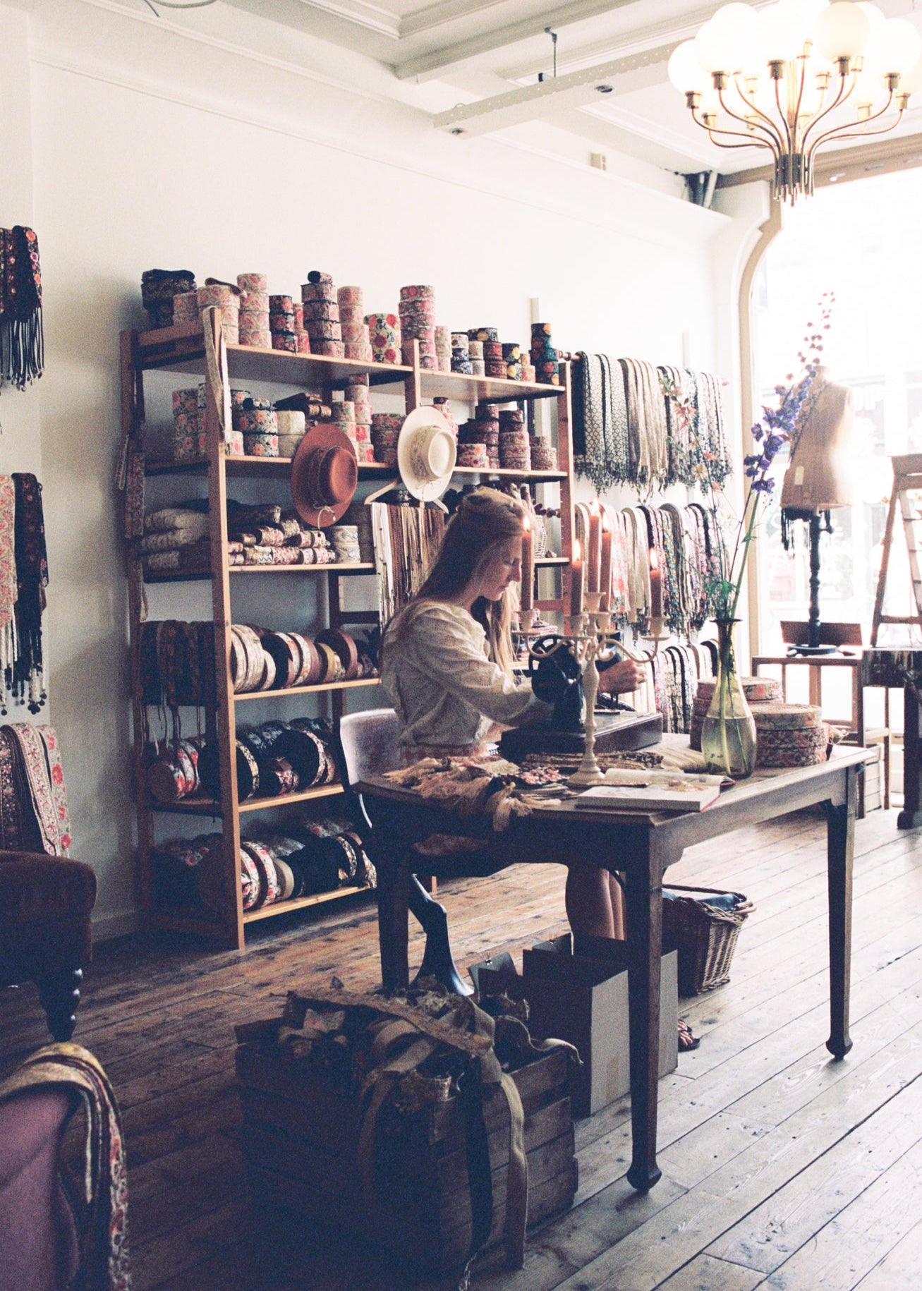 Ambachtelijk atelier met vintage naaimachine, handgemaakte stoffen en sierlijke decoratie, gevestigd in een sfeervolle ruimte in Den Haag.