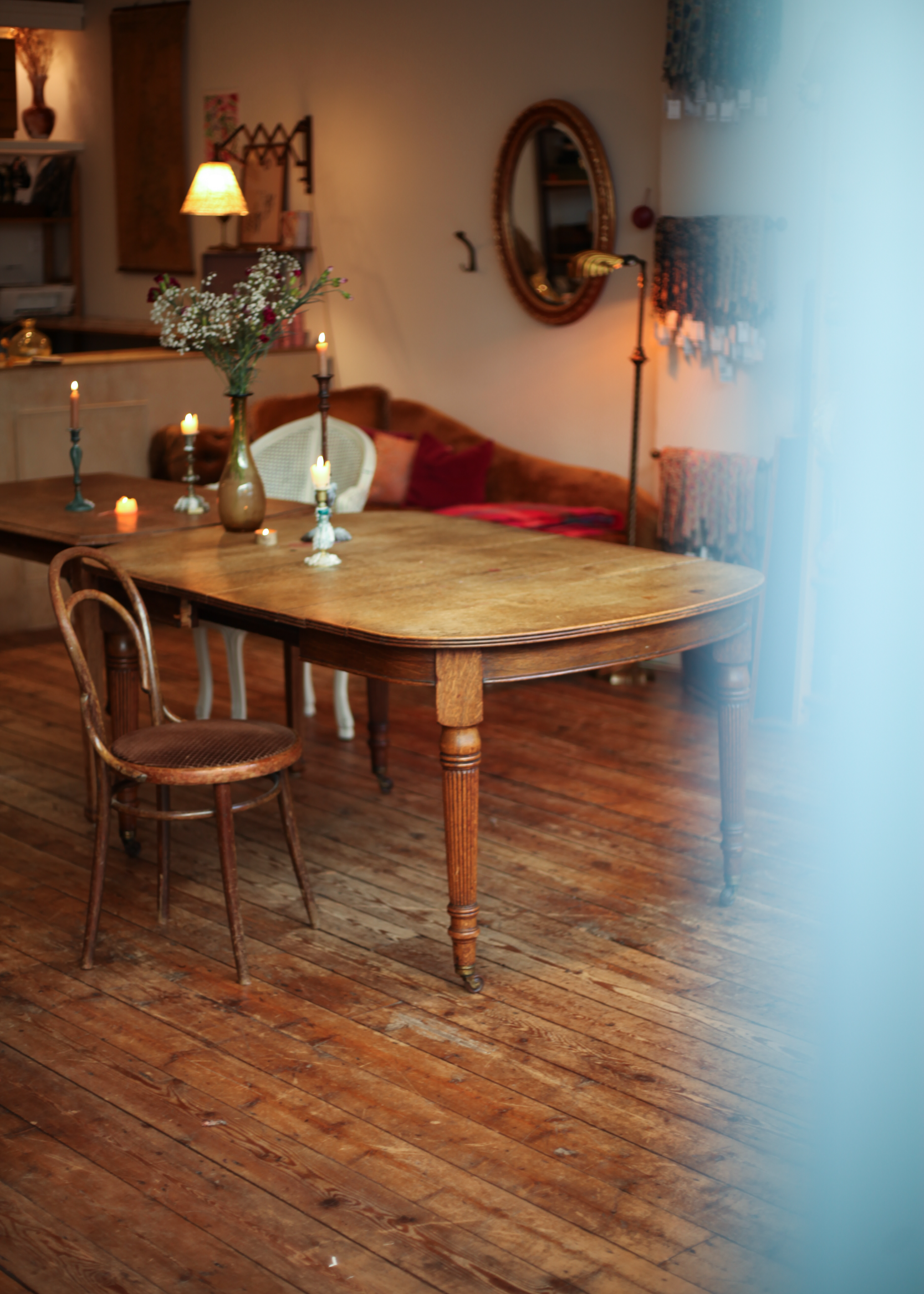 Sfeervolle evenementenruimte met een antieke houten tafel, vintage stoelen, kaarslicht en warme decoratie, perfect voor intieme bijeenkomsten in Den Haag.