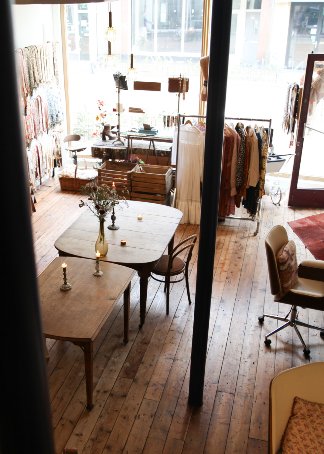 Sfeervol ingerichte conceptstore en atelier met houten tafels, kaarslicht, vintage meubels en handgemaakte accessoires in een lichte, inspirerende ruimte.