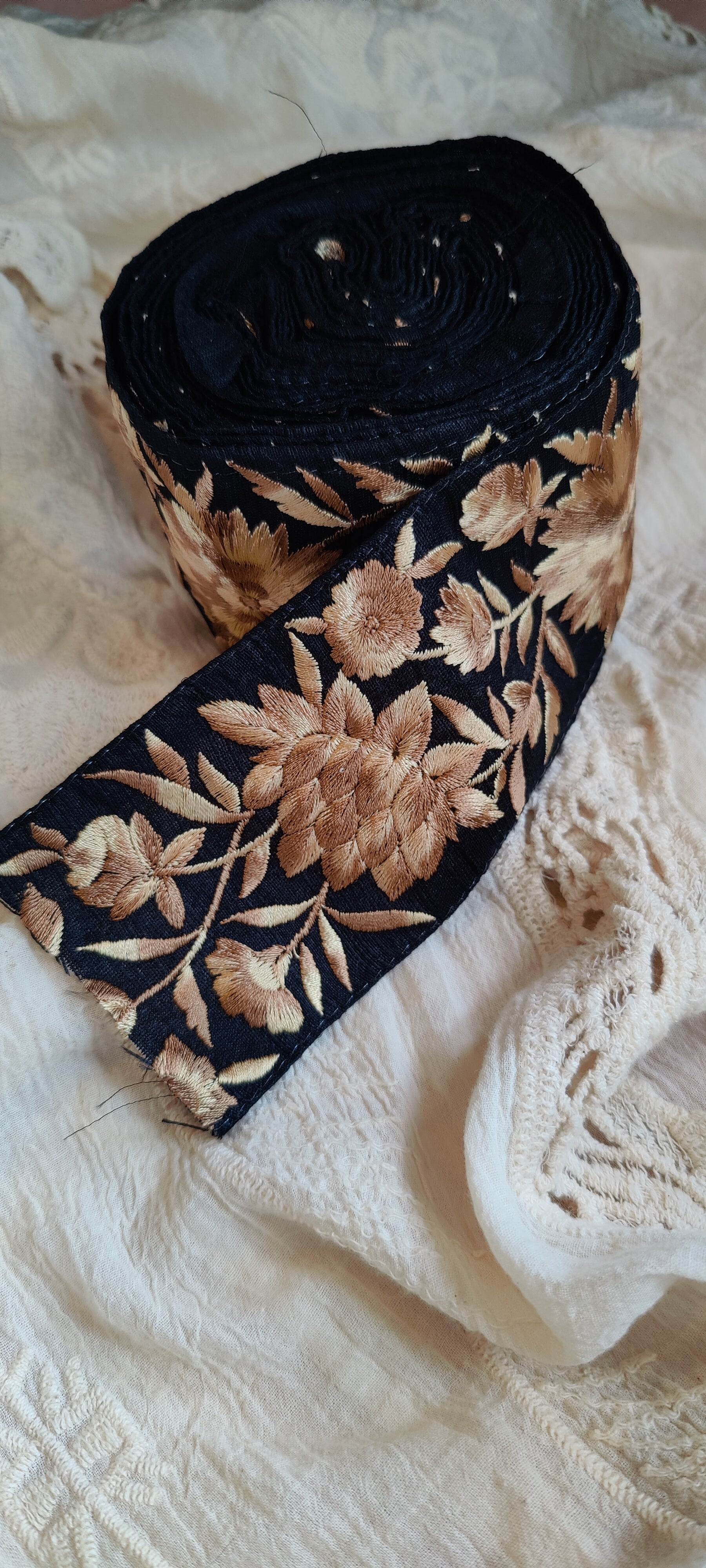 Black ribbon with floral embroidery on a textured white fabric background